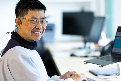 Dr Yap smiling by laptop in office